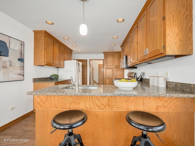 kitchen featuring sink, hanging light fixtures, dark hardwood / wood-style flooring, kitchen peninsula, and a kitchen bar