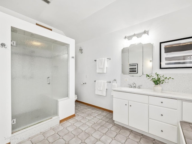 bathroom featuring vanity, toilet, decorative backsplash, and walk in shower