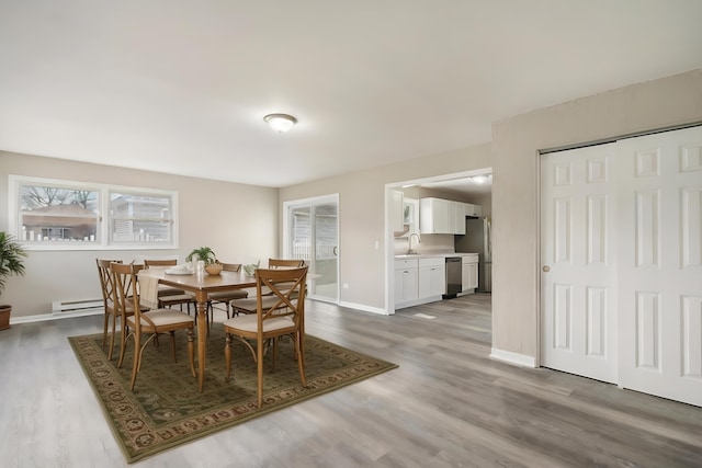 dining area featuring hardwood / wood-style flooring, sink, and baseboard heating