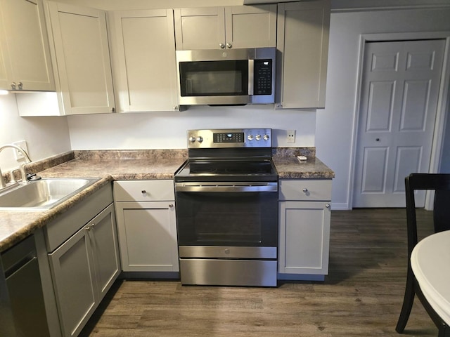 kitchen with dark wood-type flooring, sink, gray cabinets, and stainless steel appliances