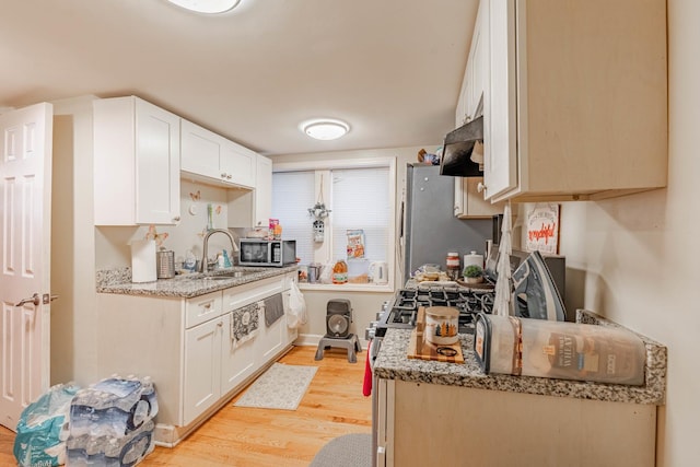 kitchen with light stone counters, stainless steel appliances, sink, light hardwood / wood-style flooring, and white cabinetry