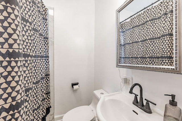 bathroom with curtained shower, toilet, and sink