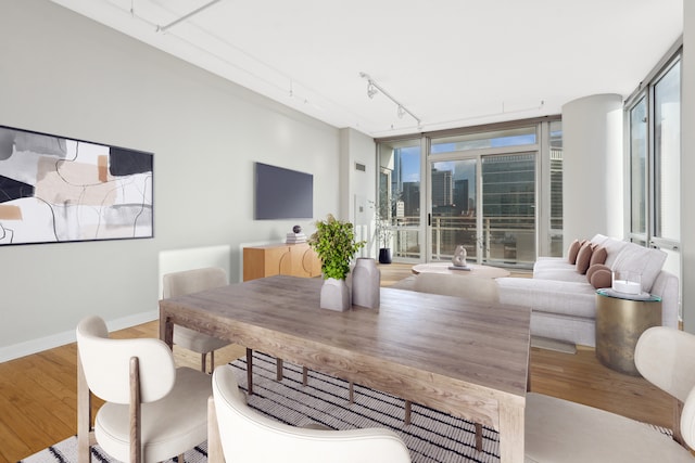 dining area with light hardwood / wood-style flooring, track lighting, and a wall of windows