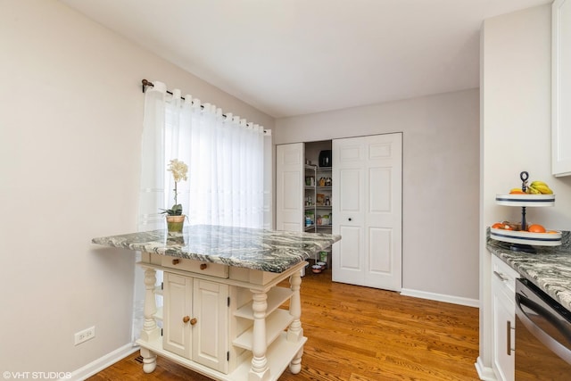 kitchen featuring dishwasher, white cabinets, light wood-type flooring, light stone counters, and kitchen peninsula