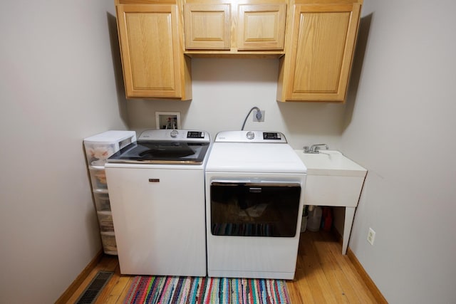 clothes washing area featuring light wood-style flooring, visible vents, baseboards, independent washer and dryer, and cabinet space