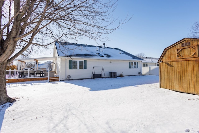 snow covered rear of property featuring an outbuilding and central AC unit