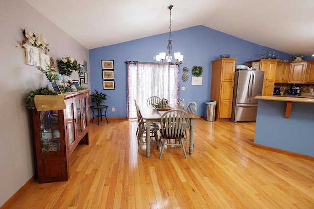 dining area with light hardwood / wood-style floors, lofted ceiling, and an inviting chandelier