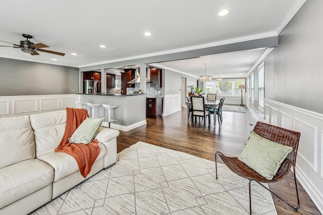 living room with light wood-type flooring, ceiling fan, and ornamental molding