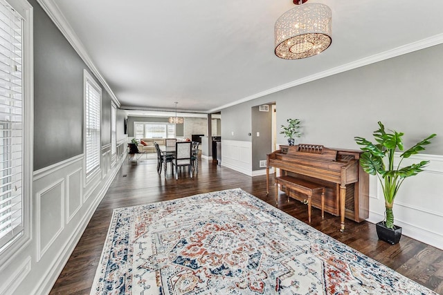 living room featuring dark hardwood / wood-style floors, crown molding, and a chandelier