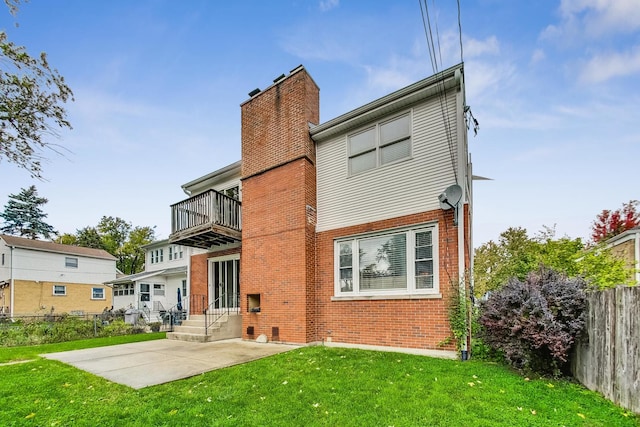 back of property with a yard, a patio, and a balcony