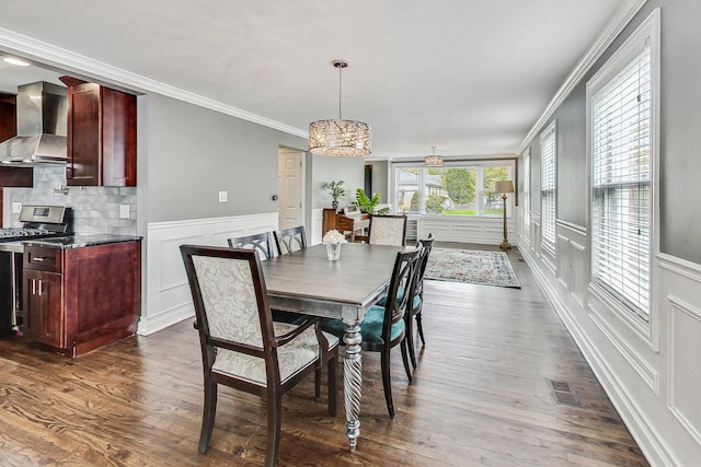 dining space featuring dark wood-type flooring, crown molding, and a chandelier