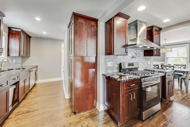 kitchen with tasteful backsplash, stainless steel appliances, sink, wall chimney range hood, and pendant lighting