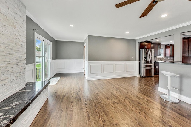 unfurnished living room featuring crown molding, sink, ceiling fan, and dark wood-type flooring