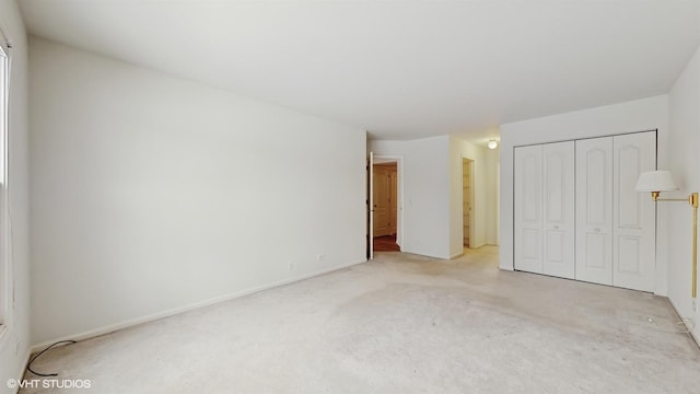 unfurnished bedroom featuring a closet and light colored carpet