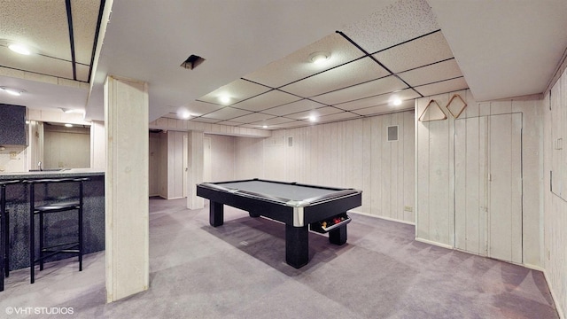 recreation room featuring a paneled ceiling, light colored carpet, wooden walls, and pool table