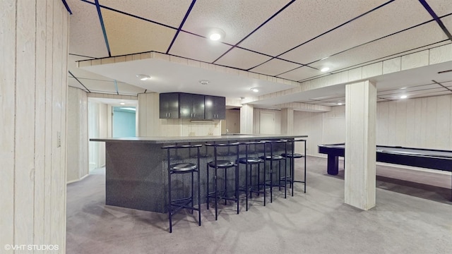 bar with a drop ceiling, wood walls, gray cabinets, light carpet, and pool table