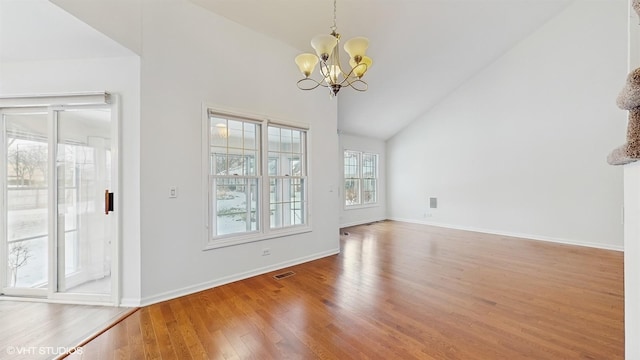 unfurnished dining area featuring hardwood / wood-style flooring, high vaulted ceiling, a wealth of natural light, and a notable chandelier