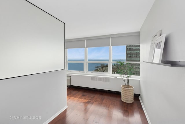 empty room featuring dark hardwood / wood-style flooring and a water view