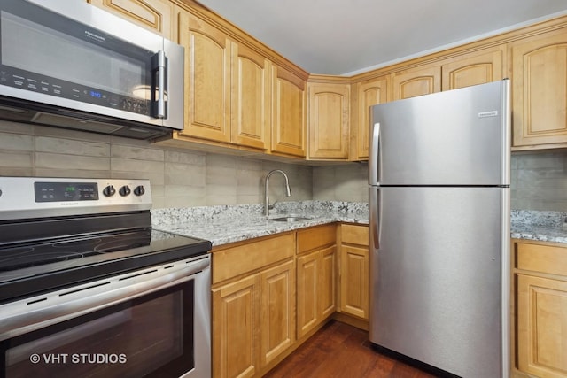 kitchen with appliances with stainless steel finishes, light stone counters, dark wood-type flooring, and sink