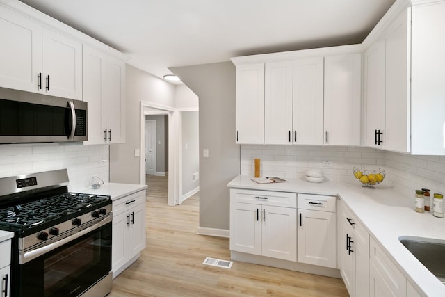 kitchen featuring white cabinets, backsplash, and stainless steel appliances