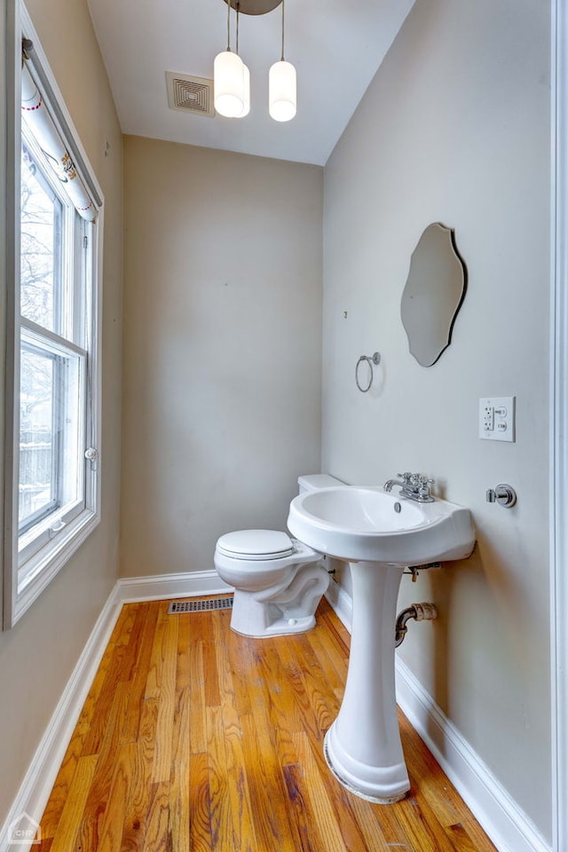 bathroom featuring hardwood / wood-style flooring, toilet, and a wealth of natural light