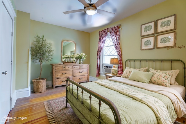 bedroom featuring cooling unit, ceiling fan, and light hardwood / wood-style flooring