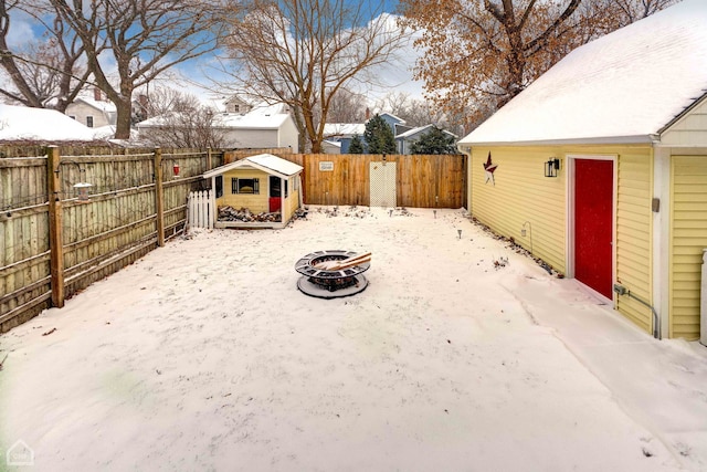 yard layered in snow with an outdoor structure and a fire pit