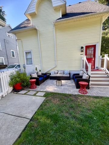 rear view of house with an outdoor living space, a patio area, and a lawn