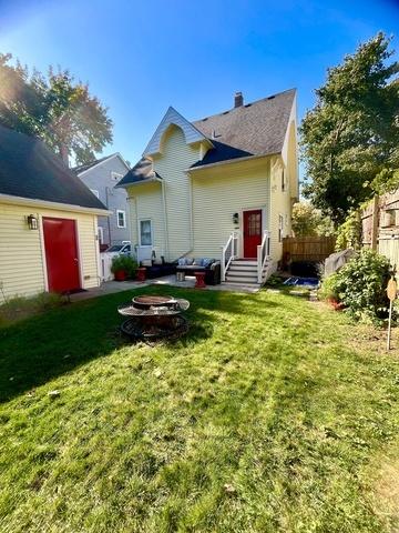 back of house featuring a lawn and an outdoor fire pit