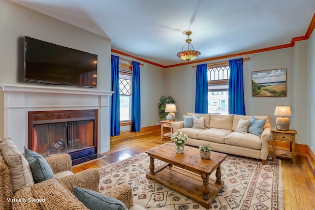 living room featuring ornamental molding, light hardwood / wood-style flooring, and a wealth of natural light