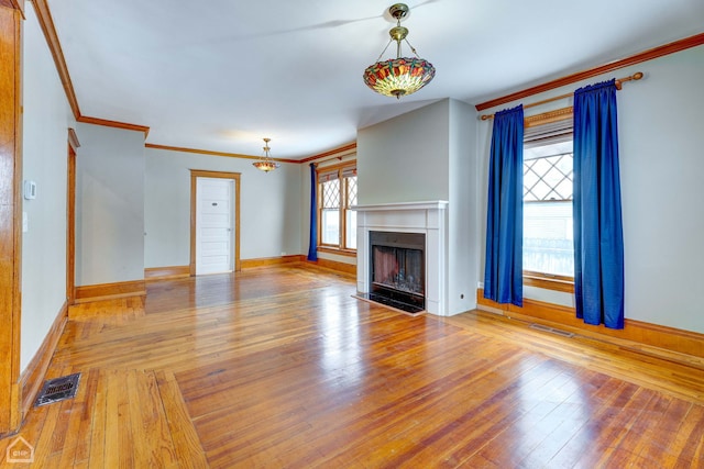 unfurnished living room featuring ornamental molding and light wood-type flooring