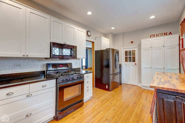 kitchen featuring wooden counters, light hardwood / wood-style floors, black appliances, white cabinets, and decorative backsplash