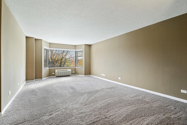 spare room featuring a wall mounted air conditioner, carpet floors, and a textured ceiling