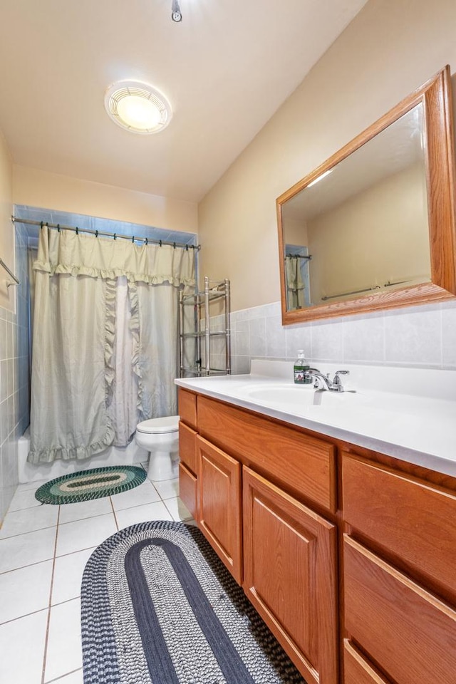 bathroom featuring toilet, vanity, tile patterned floors, and tile walls