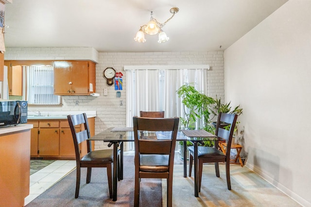 dining space featuring an inviting chandelier and brick wall