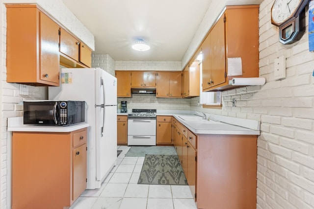 kitchen featuring brick wall, light tile patterned floors, white range oven, and sink