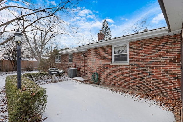 snow covered property with central AC