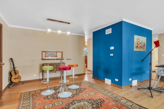 interior space featuring hardwood / wood-style floors, ornamental molding, and track lighting