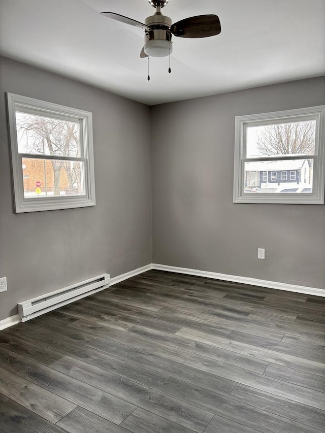 spare room featuring a baseboard radiator, a wealth of natural light, and dark hardwood / wood-style floors