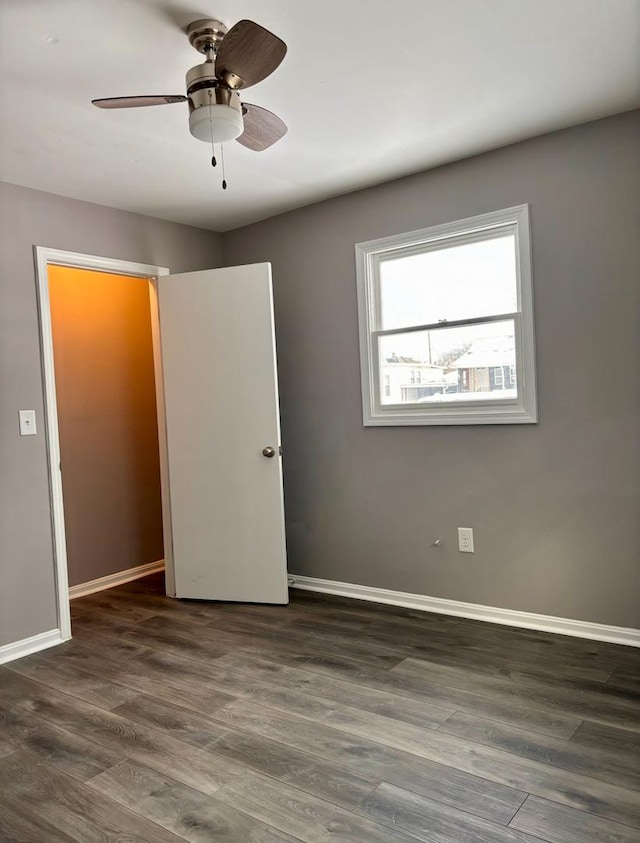 unfurnished bedroom with ceiling fan, dark wood-type flooring, and a closet