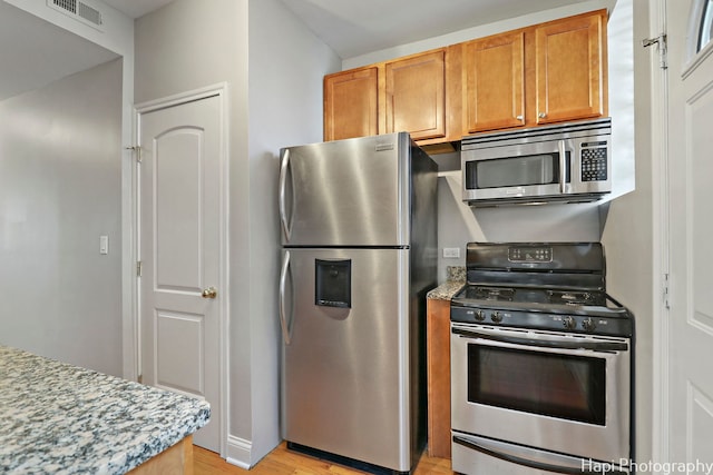 kitchen with appliances with stainless steel finishes and light hardwood / wood-style flooring