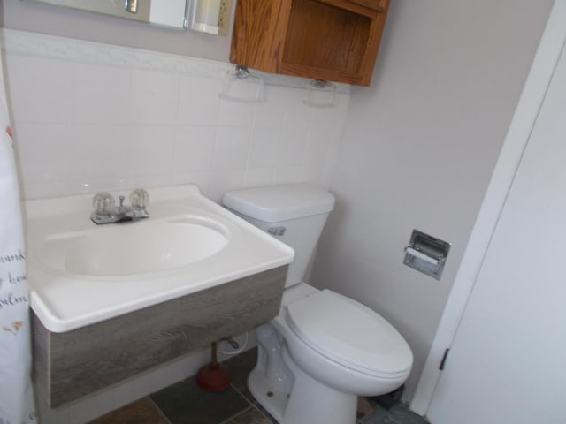 bathroom with tile patterned flooring, vanity, toilet, and tile walls