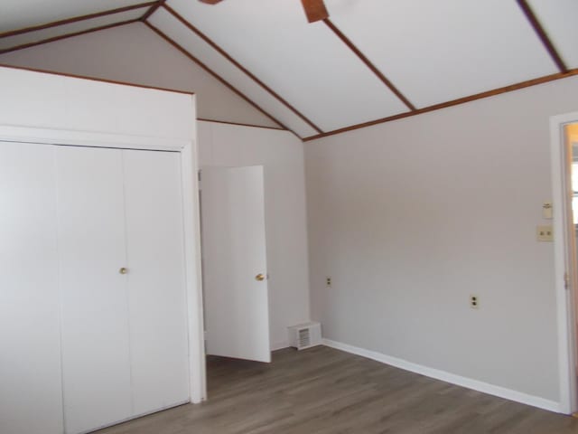 unfurnished bedroom with ceiling fan, wood-type flooring, lofted ceiling, and a closet