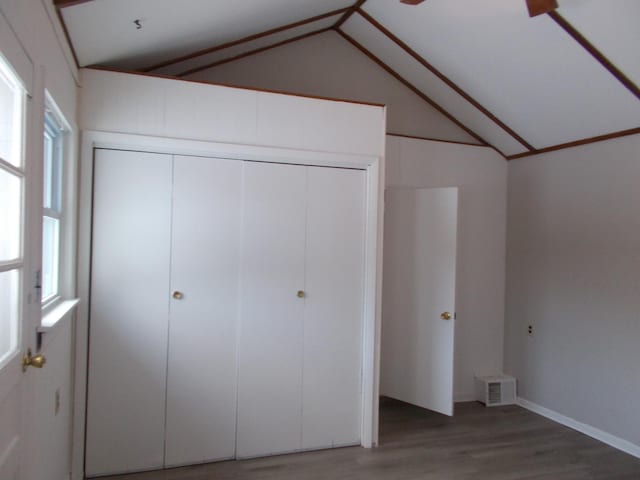 unfurnished bedroom featuring wood-type flooring, a closet, and lofted ceiling