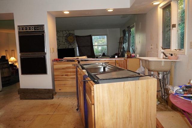 kitchen featuring light brown cabinetry, sink, double oven, and kitchen peninsula