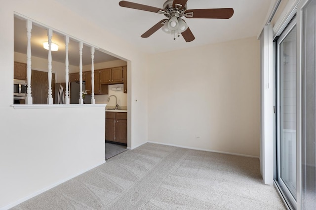 unfurnished room featuring ceiling fan, sink, and light carpet