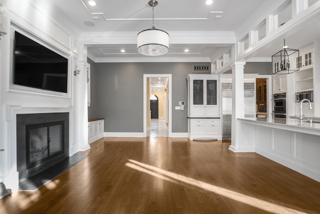 unfurnished living room featuring dark hardwood / wood-style floors, crown molding, and sink