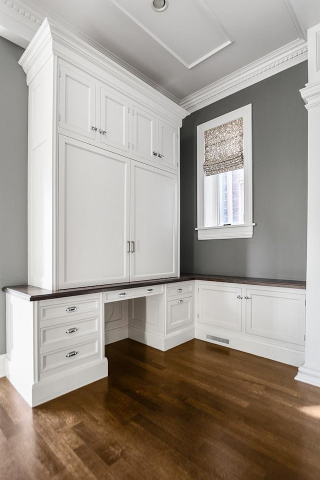 interior space featuring dark hardwood / wood-style flooring, built in desk, and crown molding