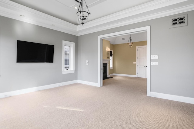 empty room with a tray ceiling, crown molding, carpet floors, and a notable chandelier