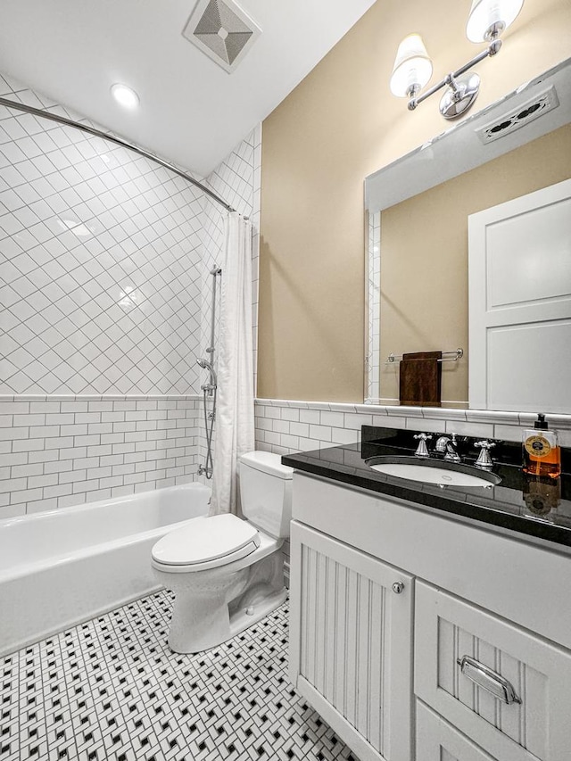 full bathroom featuring vanity, tile patterned flooring, toilet, shower / bath combo with shower curtain, and tile walls